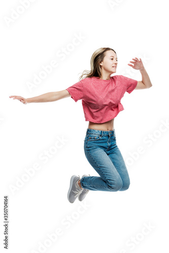 A smiling young girl in jeans and a red T-shirt is jumping. Positive and happy. Eared on a white background. Full height. Vertical.