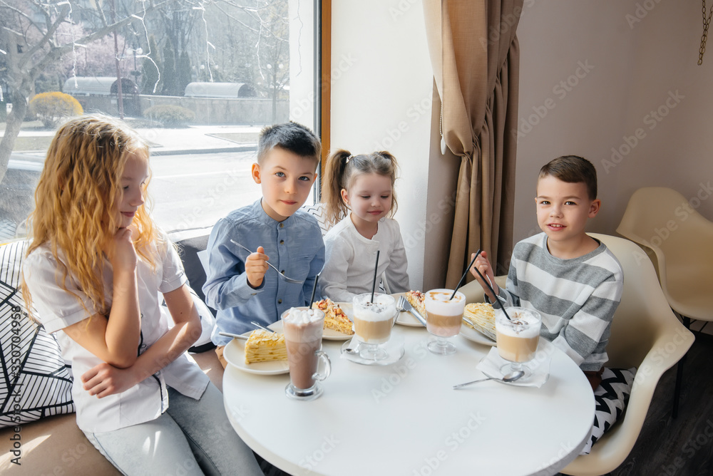 A large friendly company of children celebrate the holiday in a cafe with a delicious dessert. The day of the birth