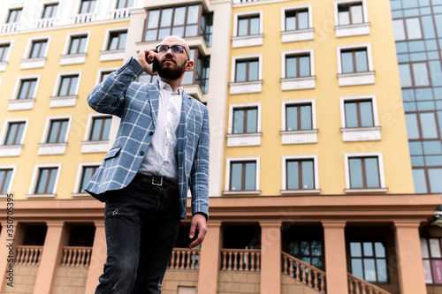 business man in a suit against the background of a beautiful building talking on the phone. outdoor