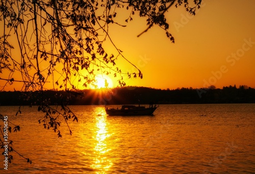 A beautiful yellow sunset with a boat in the background at the Stößensee in Berlin. 