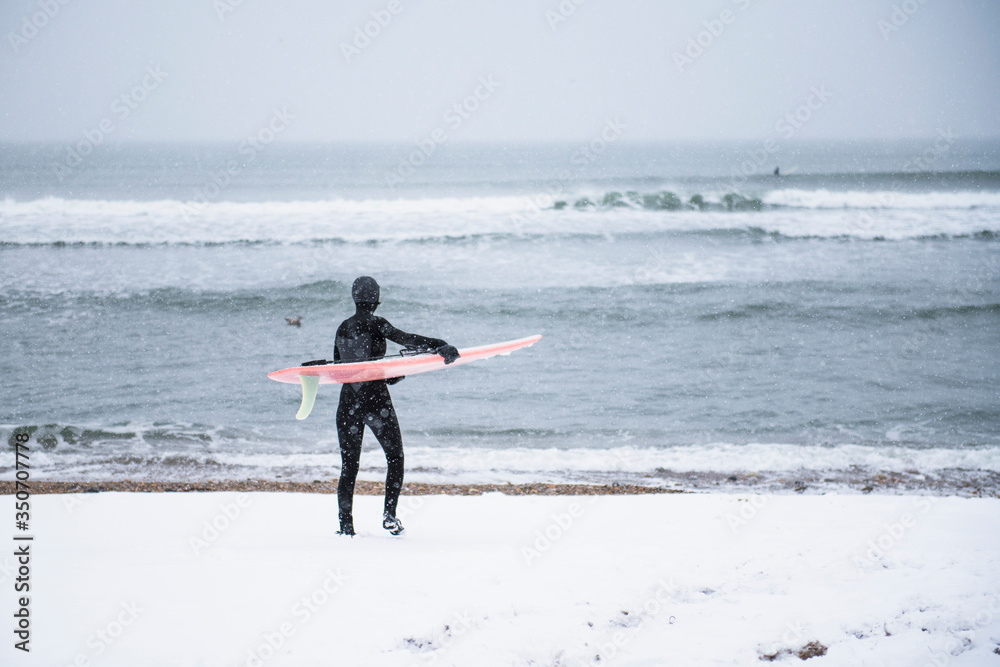 Woman going surfing during winter snow Woman going surfing during winter snow