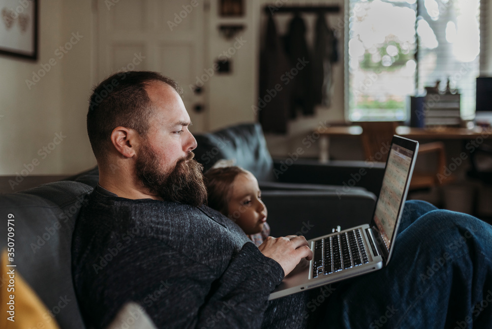 Girl looking at her father's laptop while he working from home Girl looking at her father's laptop while he working from home
