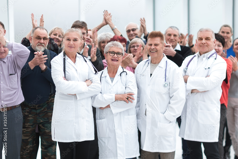 Happy doctors standing in corridor with team at hospital with crossed arms looking at camera Happy doctors standing in corridor with team at hospital with crossed arms looking at camera