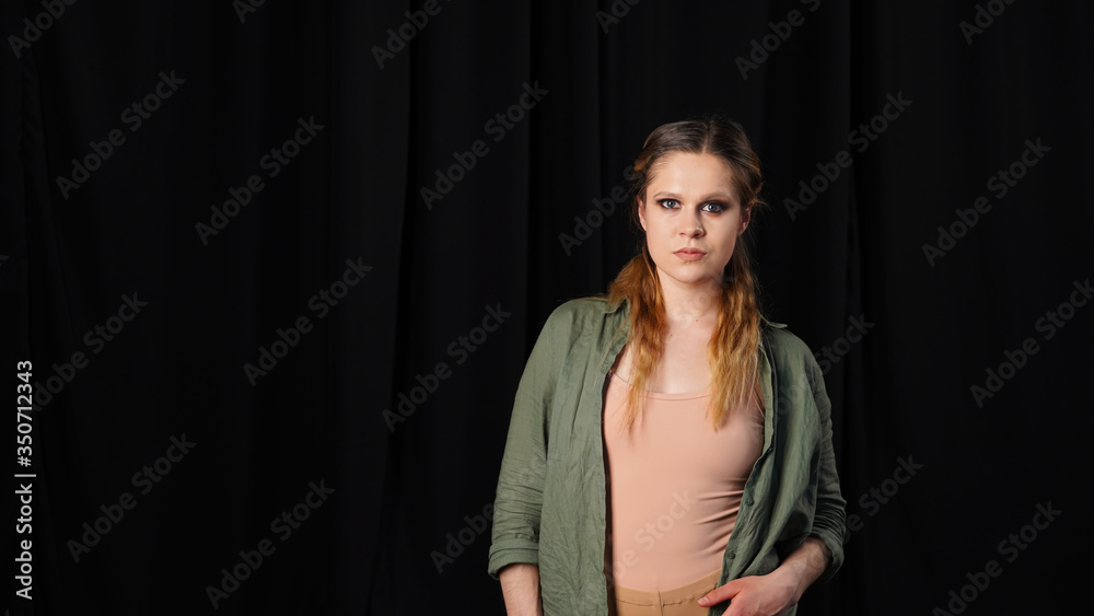 Portrait of a young beautiful girl with a sad face and asking eyes on a black background, a woman with a deep look looks into the camera lens Portrait of a young beautiful girl with a sad face and asking eyes on a black background, a woman with a deep look looks into the camera lens