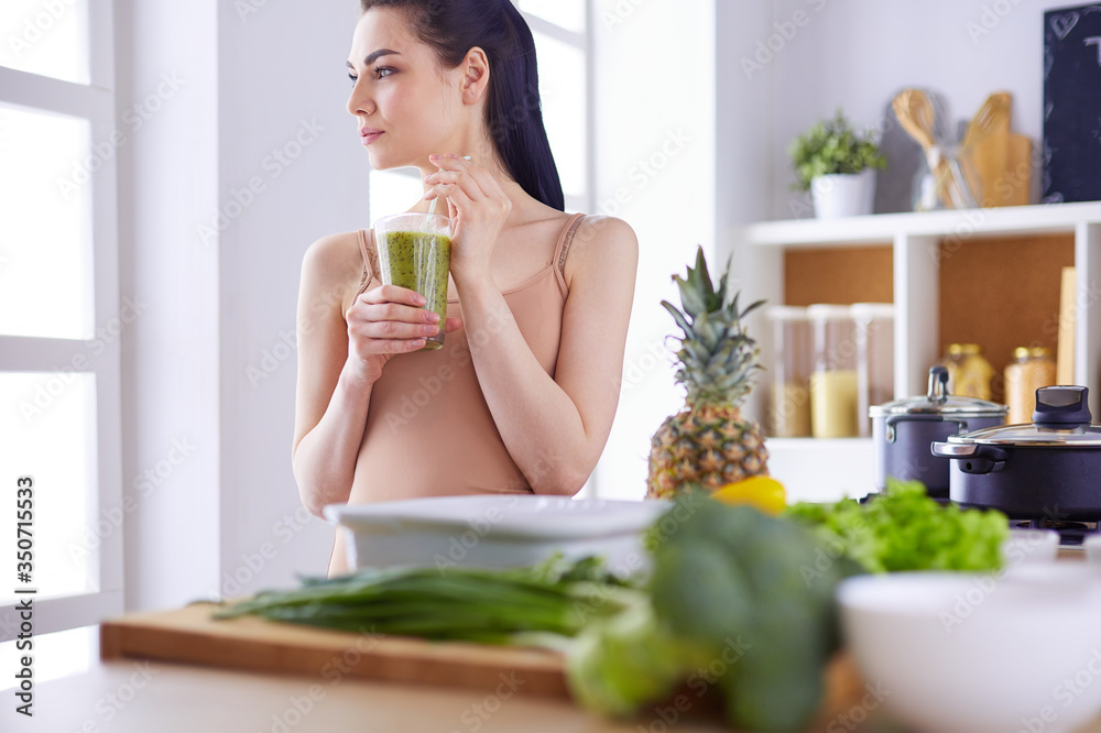 Young woman with glass of tasty healthy smoothie at table in kitchen Young woman with glass of tasty healthy smoothie at table in kitchen