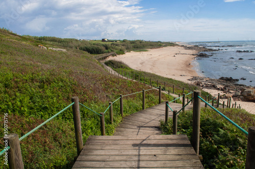 A wooden staircase leading to the white sand beach. Landscape  panorama of the ocean  beach and coastline  green grass. 