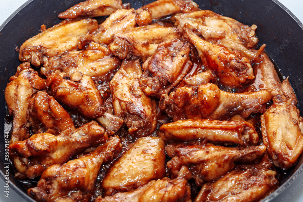 lots of fried chicken wings in a pan. close up