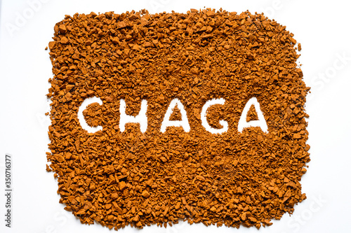 chaga mushroom. handwritten text chaga in a pile of small fragments of birch fungus chaga on a white background photo