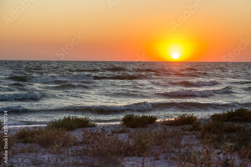 An orange sunset evening over the Black sea with big dark waves, Kinburn Foreland shore, Ukraine