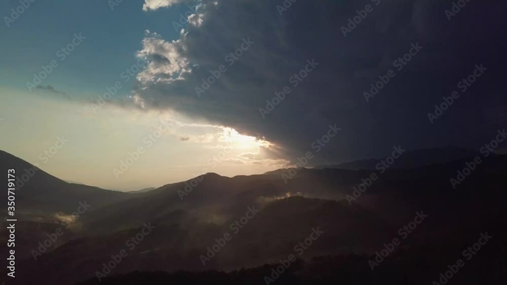 Epic sunset behind rainy clouds and fog on hills in the mountains of balkan in Greece