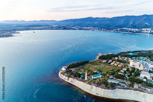 Entrance from a height to the Gelendzhik Bay at sunset in calm, windless weather. In the foreground is a "Thick" Cape with a lighthouse, in the background is a "Thin" Cape.