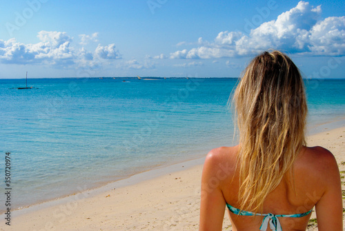 Young woman on tropical beach looking at the horizon.