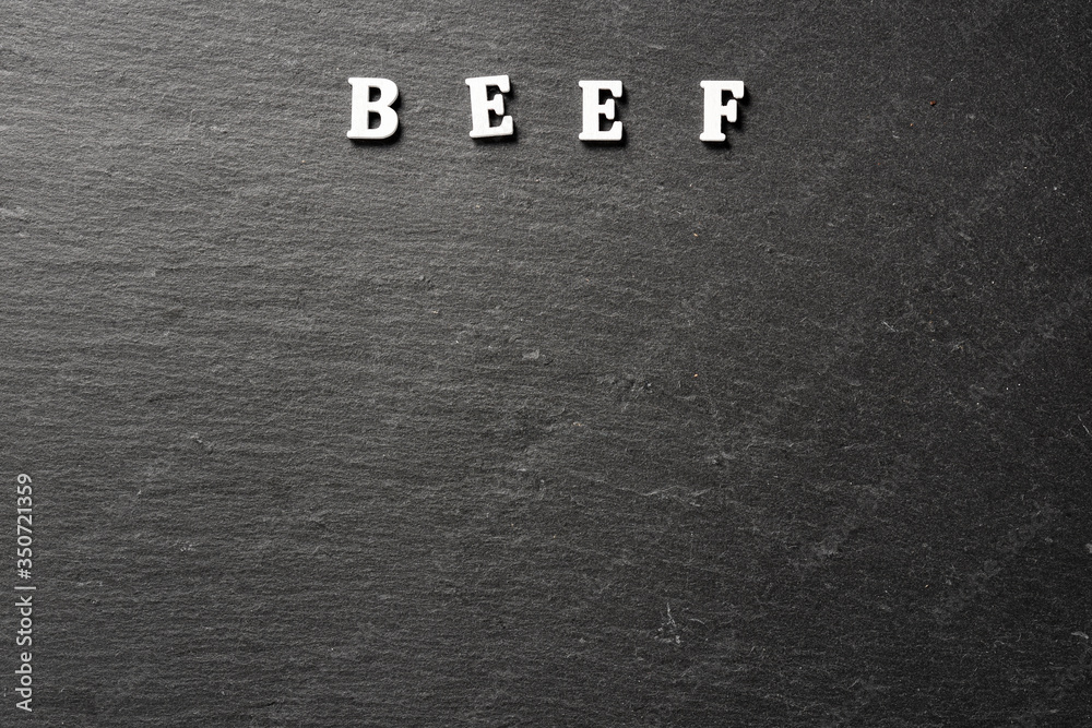 Fototapeta Beef word on black stone desk