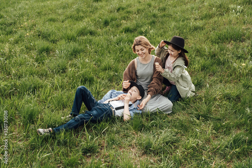 Happy family, mom daughter and son in organic clothes, walk in the field and eat ice cream. The concept of a healthy lifestyle, happiness and joy