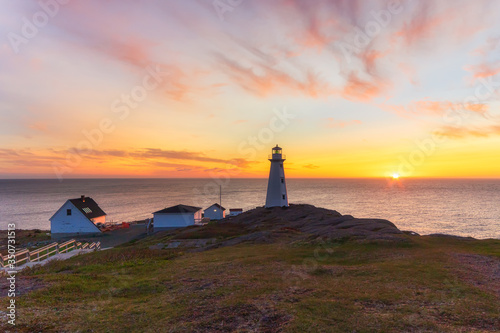 Fotografija Beautiful sunrise over a white lighthouse sitting at the edge of a rocky cliff