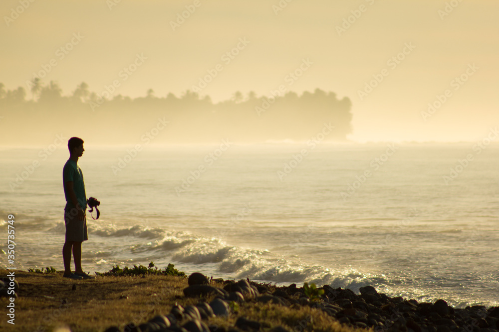 photographer man walking on the beach at sunset
