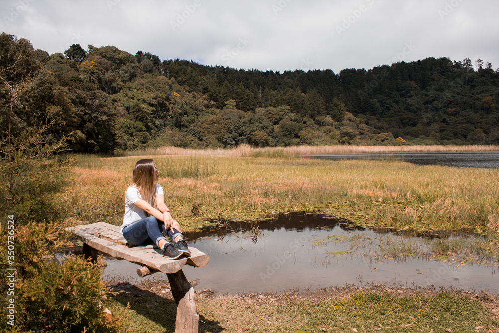 young woman sitting on the edge of a lake
