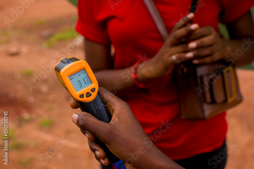young black woman's hand holding a handheld infrared thermometer