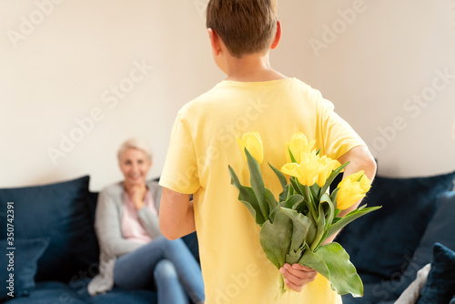 Boy kid giving a tulips to her mom. photo