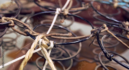Rusted metal wire chair coils exposed in an antique wooden chair seat.  Rows of metal spirals with jute twine rope. Laid out in an array of pattern.  Chair is a vintage rocker.