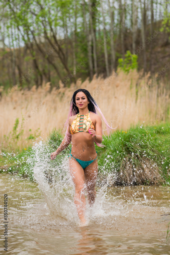 Fototapeta premium sexy girl with pigtails in a swimsuit on the beach by the lake.