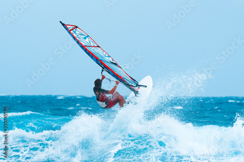 summer sports: windsurfer riding the waves during the holidays on the atlantic blue ocean water.