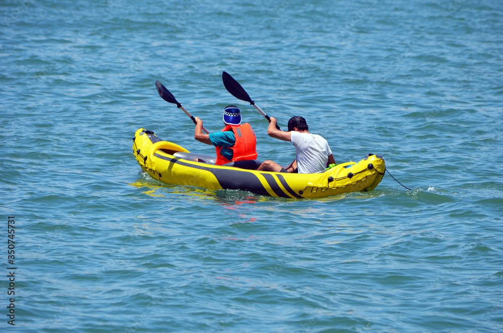 
two men kayaking on biscayne bay in a yellow inflatable kayak.