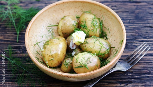 Young boiled potatoes with butter and dill on a wooden background of an old tree. country style. Organic food. copy space