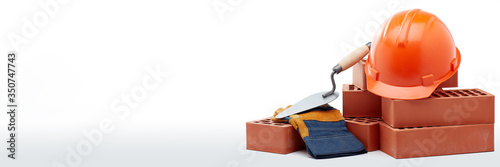 Stack of bricks with masonry trowel,  construction hard hat and gloves on white background. Construction concept.