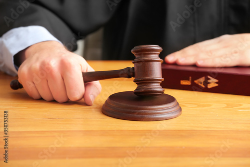 Male judge with gavel at table in courtroom, closeup