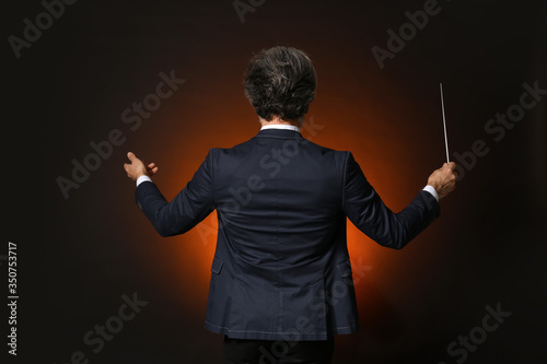 Senior male conductor on dark background photo
