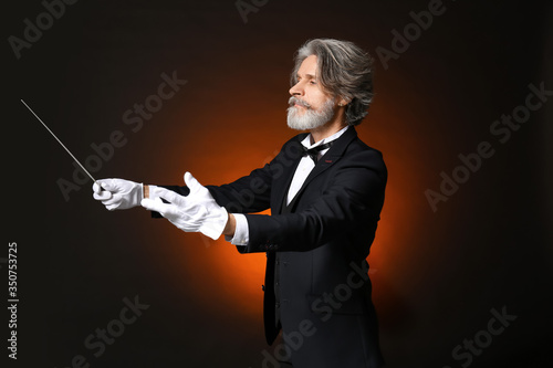 Senior male conductor on dark background photo