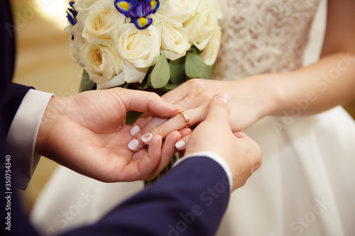 Bride and groom exchange rings at the wedding. Lovers put each other rings on the fingers.