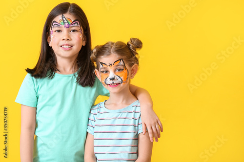 Funny children with face painting on color background