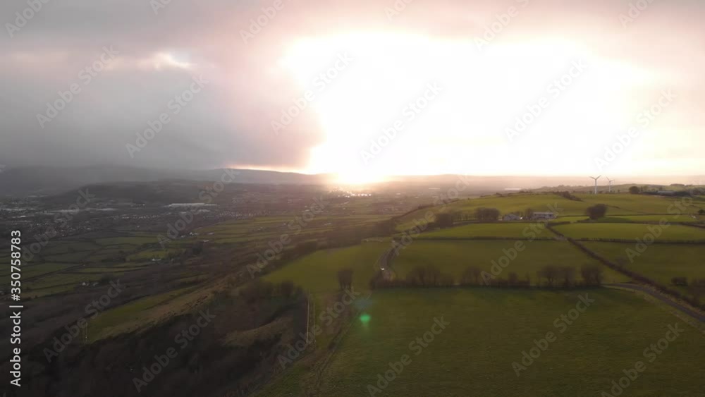 Panning shot of Irish countryside in County Antrim, with wind farm and beautiful sunset in background Panning shot of Irish countryside in County Antrim, with wind farm and beautiful sunset in background