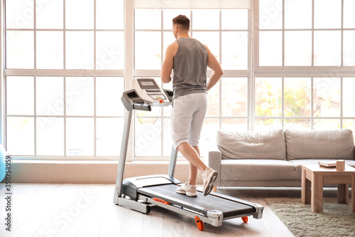 Canvas Print Young man training on treadmill at home