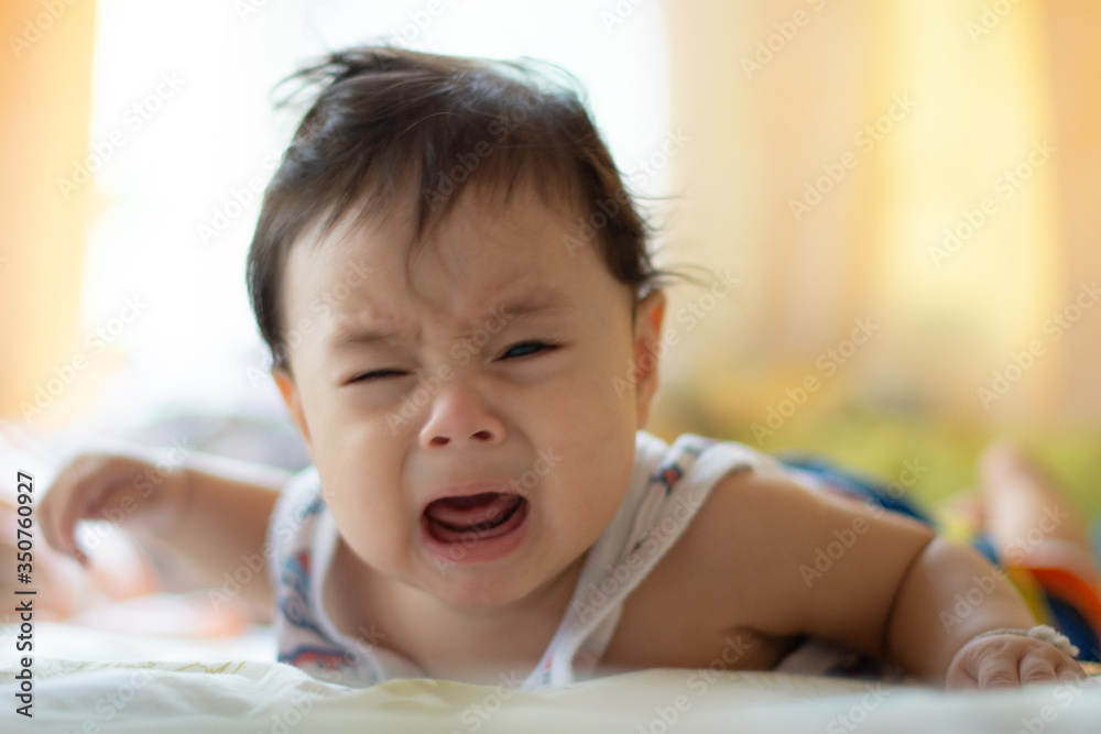 Portrait of infant baby boy crying and screaming lying on bed Portrait of infant baby boy crying and screaming lying on bed