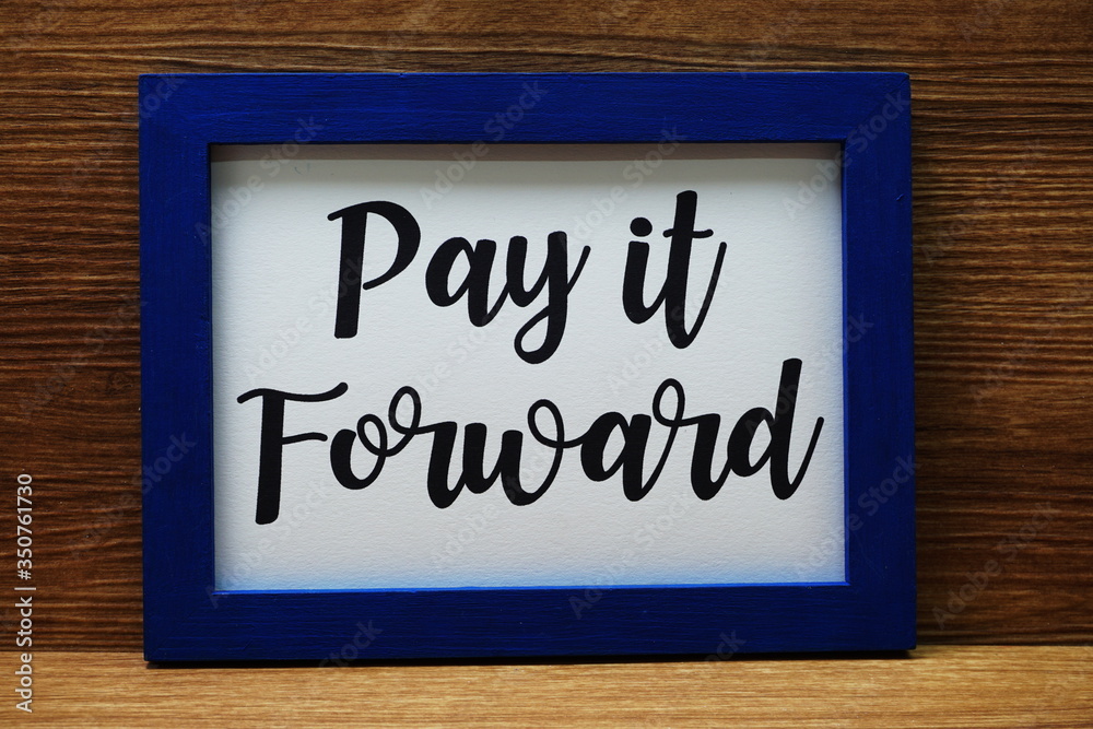 Pay It Forward written with blue photo frame on wooden background Pay It Forward written with blue photo frame on wooden background