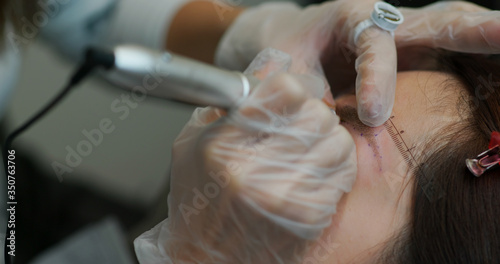 Woman undergo eyebrow microblading, permanent makeup