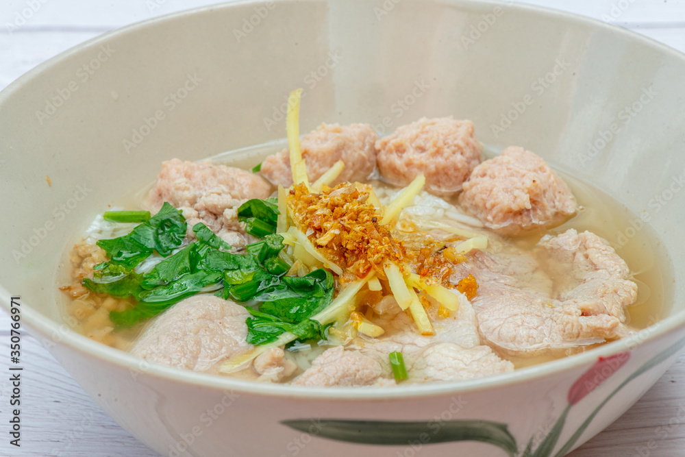 Thai Breakfast, Hot Thai rice soup with pork and meat on bowl with white wood background Thai Breakfast, Hot Thai rice soup with pork and meat on bowl with white wood background