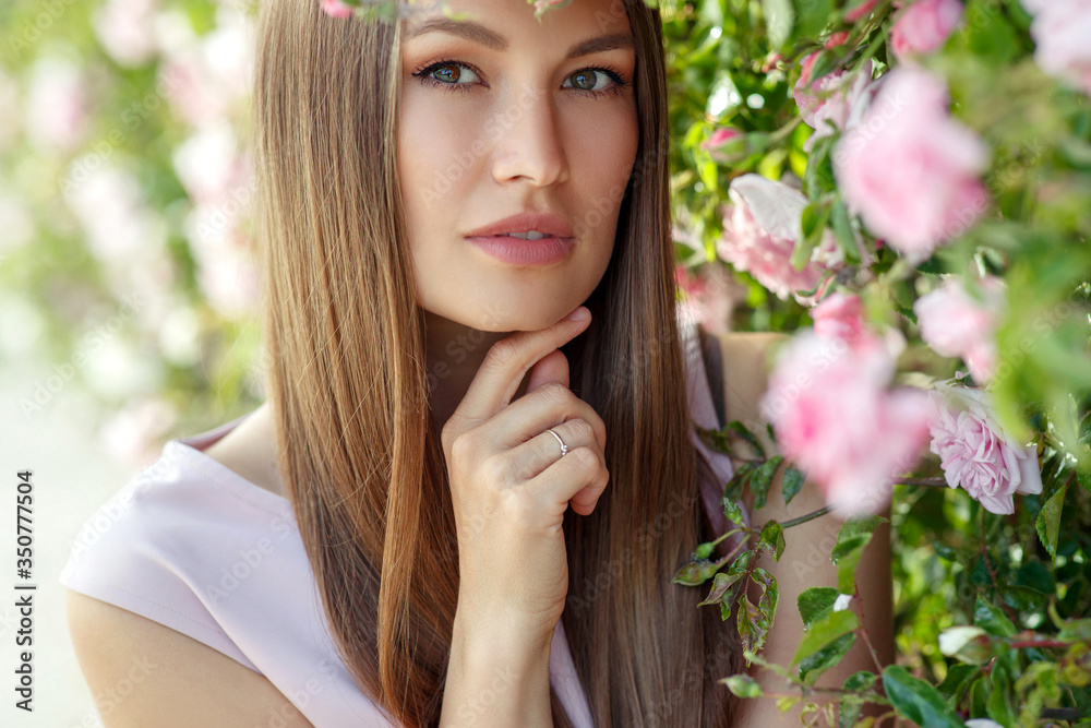 Beautiful young woman in nature in roses. Brunette girl with roses. Beautiful young woman in nature in roses. Brunette girl with roses.