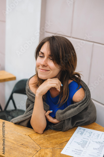 A girl sits on a summer terrace of a cafe waiting for her order