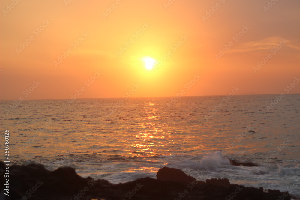Beautiful blazing sunset landscape at black sea and orange sky above it with awesome sun golden reflection on calm waves as a background. Amazing summer sunset view on the beach. 
