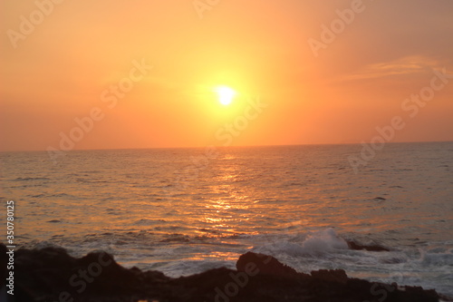 Beautiful blazing sunset landscape at black sea and orange sky above it with awesome sun golden reflection on calm waves as a background. Amazing summer sunset view on the beach. 