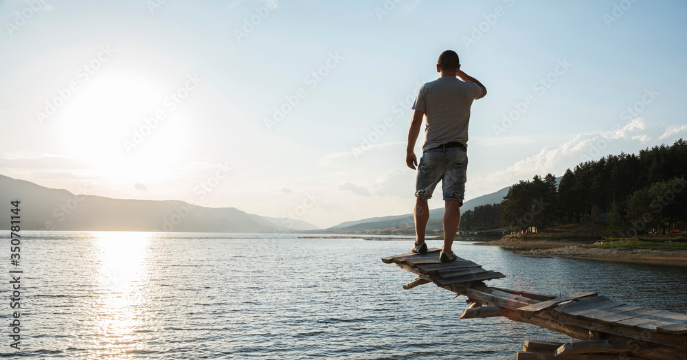 Boy in front of mountain lake