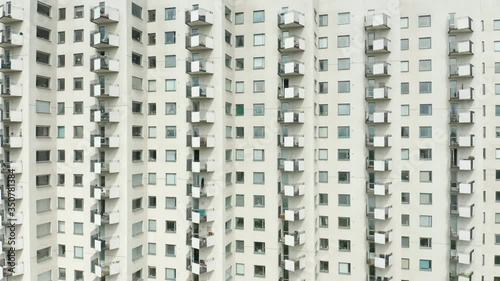 Exterior of a high rise multi story residentail apartment building - white facade, windows & balconies. Establishing shot aerial footage. photo