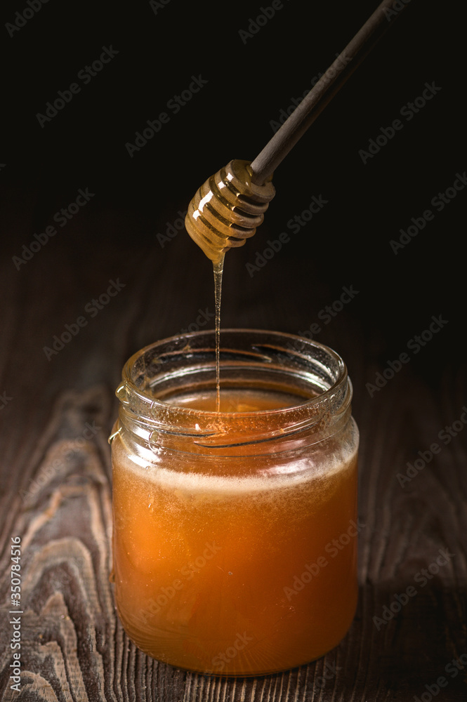 Honey with wooden honey dipper on wooden table