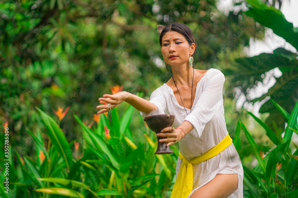 mind and body connection - beautiful and happy healer Asian woman holding incense cup doing ritual traditional healing dance at green tropical forest in wellness mind and body connection - beautiful and happy healer Asian woman holding incense cup doing ritual traditional healing dance at green tropical forest in wellness
