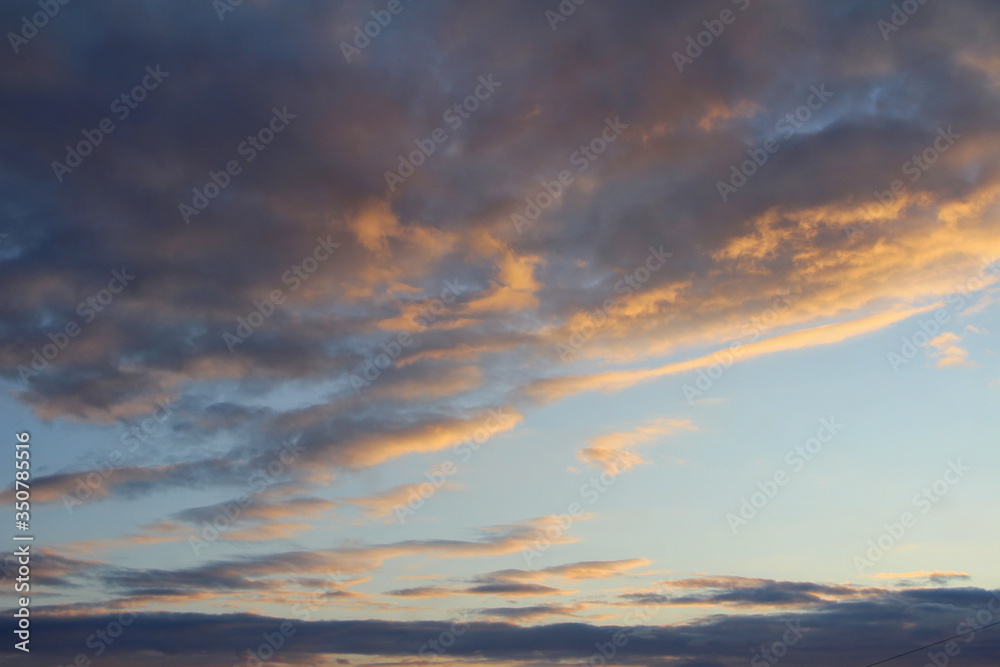 Clouds in the sky are illuminated from below by the red light of the sun. Sunset or sunrise scene at dusk.