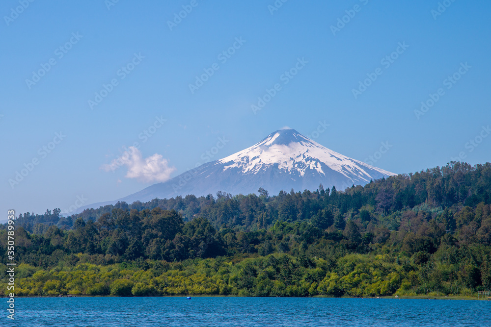 Villarrica volcano with a snow-capped peak against a blue sky. View from Villarrica Lake in the Pucon town. Chile